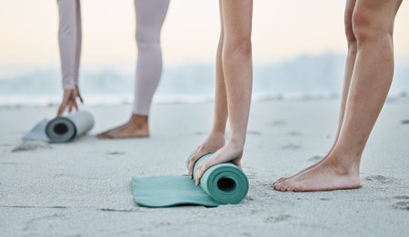 Fitness, beach and women roll yoga mat getting ready for workout, exercise or stretching. Zen, meditation or hands of females, girls or friends outdoors on beach sand rolling mat for pilates trainingの写真素材