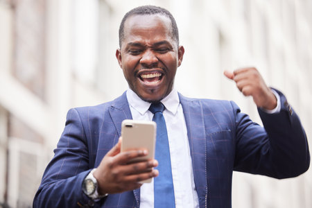 Success, phone or happy businessman in a city in celebration of good news, job promotion or sales goals. Winner, wow or excited black man celebrates winning a bonus or successful financial investmentの写真素材