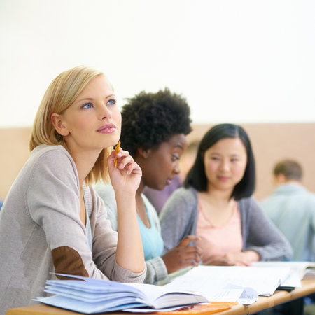 Thinking of the weekend...female university students sitting in an exam room.の写真素材