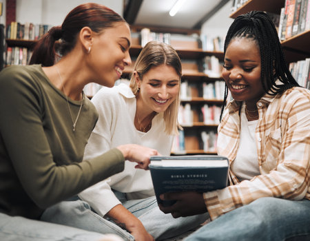 Student, friends and book in school library for education, learning or knowledge together at university. Students smile for book club, books or information for research assignment or group projectの写真素材