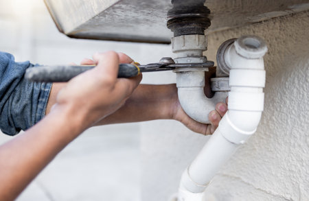 Hands, tool and pipe with a man plumber fixing a water system as a DIY handyman for maintenance. Building, construction or plumbing with a professional contractor working to install pipeline drainageの写真素材