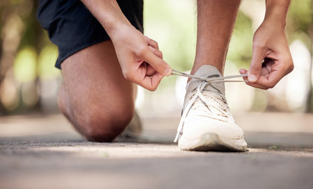 Park, shoelaces and ground with man hands, outdoor adventure and training for wellness in summer. Shoes, sneakers and start morning for fitness, exercise and strong body development in nature parkの写真素材