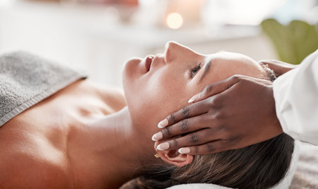 Face massage, spa and skincare woman with luxury wellness, peace and calm for beauty treatment. Facial therapist and hands for person zen, healing and stress relief while relax on table in bokehの写真素材