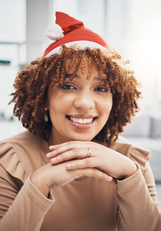 Santa hat, black woman and portrait of a female at home getting ready for christmas and holiday. House, smile and happiness of a young person celebrating holidays in an apartment with fun accessoriesの写真素材
