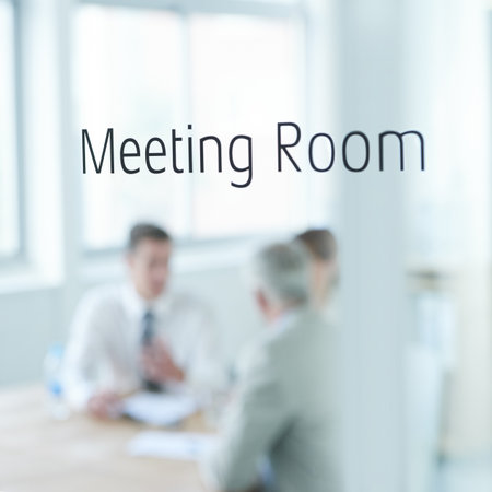 Behind closed doors. Closeup of a glass door reading meeting room with business people blurred in the room behind.の写真素材