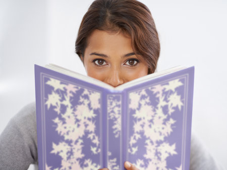 Interesting read. Portrait of a young woman peering over a book.の写真素材