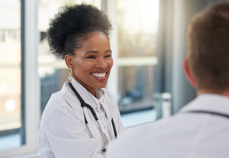 Doctor, happy black woman and meeting healthcare team for hospital management, medicine and discussion. Female surgeon, smile and talking to employees in collaboration, surgery and medical planningの写真素材