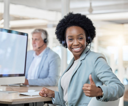 Happy, portrait and black woman in a call center with a thumbs up for online support and thank you. Smile, success and African customer service worker with an emoji hand gesture for achievementの写真素材