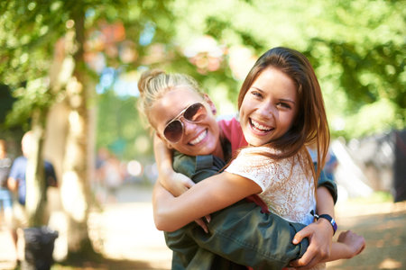 Girls day out. Two female friends hugging while standing outside.の写真素材