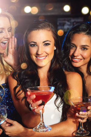 Women, cocktail drink and party with smile in portrait, friends on night out for new year...
