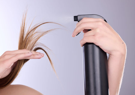 Hair care, beauty and hands with spray in studio isolated on a gray background. Cosmetics product,...