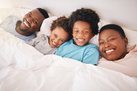 Smile, happy and relax with black family in bedroom for bonding, wake up and morning routine from top view. Care, funny and cute with parents and children at home for calm, weekend and quality timeの写真素材