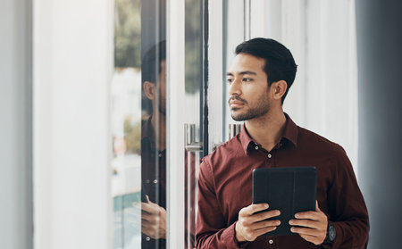 Tablet, window and Indian businessman thinking, concentration and planning digital project idea. Startup, development and assessment online for new property design, architect brainstorming in office.の写真素材