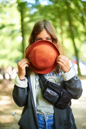 Shy style. A young woman standing outside peeking over the rim over her hat.の写真素材
