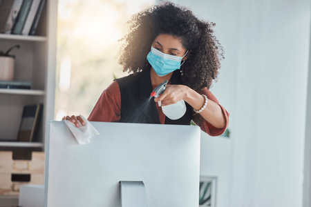 Covid, compliance and a black woman cleaning her computer in the office for health, safety or...