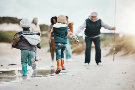 Happy, running and family at the beach for fishing, freedom and excited about vacation. Smile, greeting and kids at the ocean with grandfather, parents and grandmother to fish during a holidayの写真素材