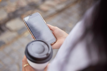 Phone, coffee and screen with a woman in the city browsing social media or typing a text message from above. Contact, texting and 5g mobile technology with a female person outside in an urban townの写真素材
