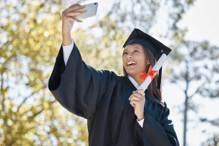 Selfie, smile and graduation of woman with certificate in university or college campus. Graduate, education scholarship and happy female student taking pictures to celebrate academic achievement.の写真素材