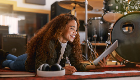 Black woman, smile and tablet writing music in recording studio for audio track, content creation or development. Happy African female song writer smiling in lyrics holding touchscreen lying on floorの写真素材