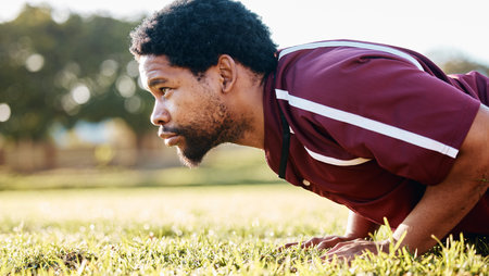 Sports, workout and man doing a push up on the field for training or practice before a game....