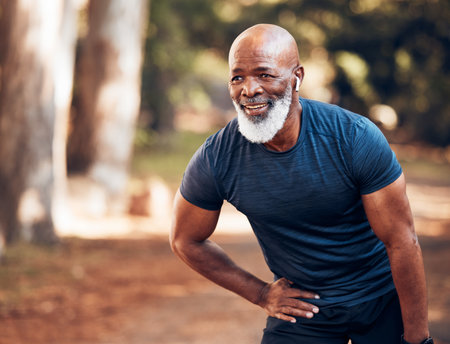 Black man, break from running and relax with fitness, vitality and cardio, senior runner in the park. Exercise, earpods and listen to music for motivation, tired with endurance and health outdoorの写真素材