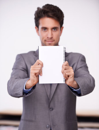 A message from the boss. A young businessman holding up a notepad.の写真素材