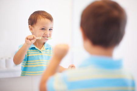 Hes learning healthy hygiene. a cute young boy brushing his teeth in a mirror.の写真素材