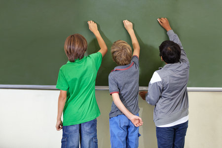 The best way to learn. three children writing on a black board.の写真素材