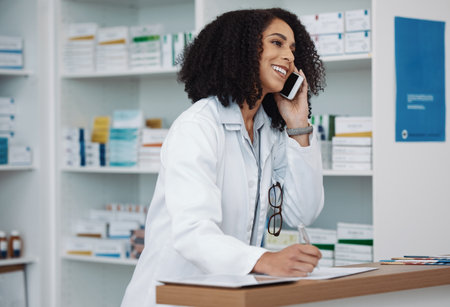 Phone call, counter and pharmacy woman for medicine, customer service or virtual healthcare support. Happy, friendly and expert doctor, medical person or pharmacist talking on cellphone at help deskの写真素材