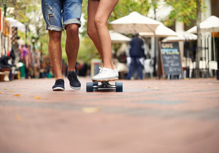 Taking it one ride at a time...a young couples legs with one balancing on a skateboard,.の写真素材