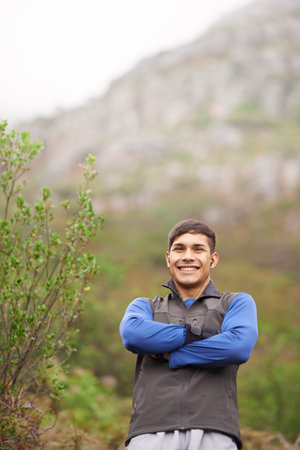 Enjoying a scenic workout. A smiling male with his arms crossed standing in the outdoors.