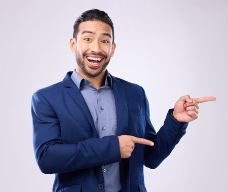 Happy, portrait and man in a studio pointing to mockup for marketing, advertising or product placement. Happiness, smile and male model from India with showing gesture for mock up by gray background.の写真素材
