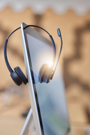 Call center headset, computer and nobody in empty office for telecom, virtual communication or telemarketing background. Callcenter business with desktop screen or pc for online customer servicesの写真素材
