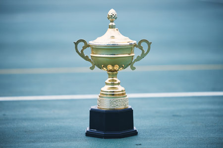 Trophy, award and target with a sports cup on an empty court outdoor for the winner, champion or victor. Gold, goal and success with a prize on the floor outside at a stadium or arena for sportの写真素材
