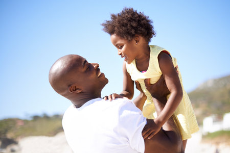 You mean the world to me. A father lifting his adorable daughter into the air while enjoying a day at the beach.の写真素材