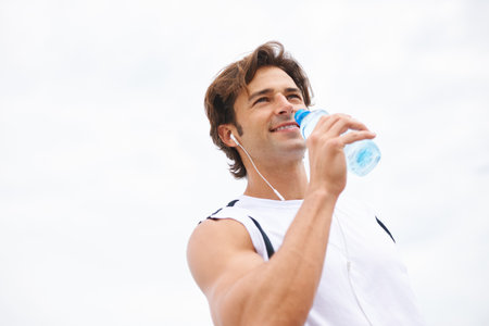 Staying hydrated. a handsome young man taking a drink of water while working out.の写真素材