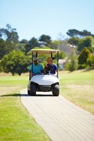 Enjoying a sunny day game. two friends driving a golf court out on the course on a sunny day.の写真素材