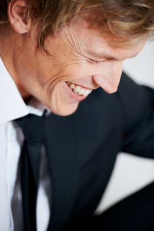 Its a laughing matter. a young businessman laughing against a grey background.の写真素材