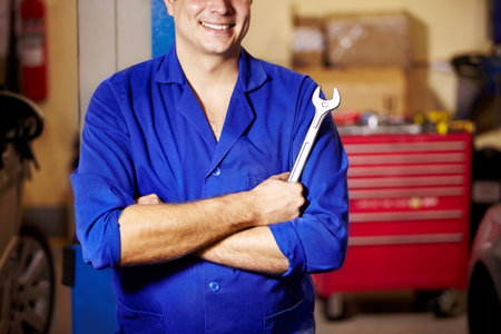 Hes confident in his work. Cropped image of a male mechanic standing confidently while holding a spanner.の写真素材