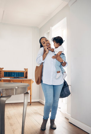 I think mom needs a nanny. a young woman looking annoyed while talking on a cellphone and carrying her daughter at home.の写真素材