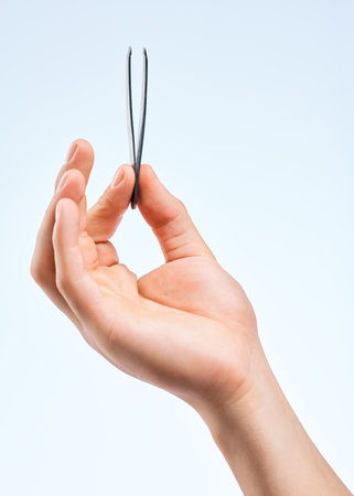 For those pesky hairs. an unrecognizable man holding a tweezer against a white background.の写真素材