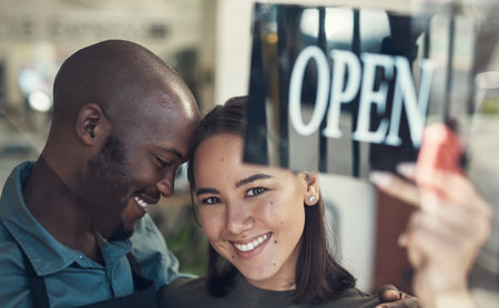 She makes me so unbelievably proud. a young couple standing together and turning the sign on the door to their bicycle shop.の写真素材