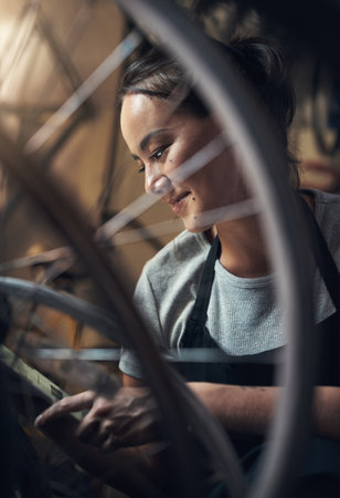 Never been happier to put in the extra time. a happy young woman using a digital tablet and fixing a bike at a bicycle repair shop.の写真素材