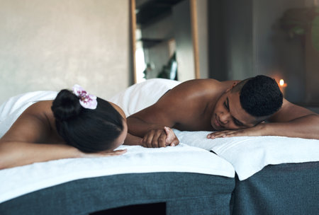 Its been a great bonding experience for them. a young couple relaxing on massage beds at a spa.の写真素材