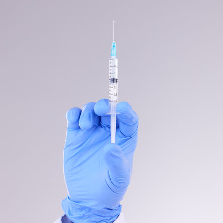 Hands, vaccine and healthcare with a doctor in studio on a gray background holding monkeypox treatment. Medical, innovation and insurance with a medicine professional ready to administer a cureの写真素材