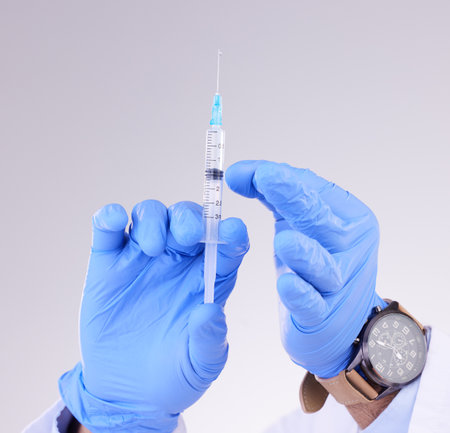 Hands, vaccine and healthcare with a doctor in studio on a gray background holding monkeypox treatment. Medical, innovation and insurance with a medicine professional ready to administer a cureの写真素材