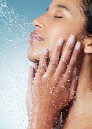 My skin feels so good after my shower. an attractive young woman showering against a blue background.の写真素材
