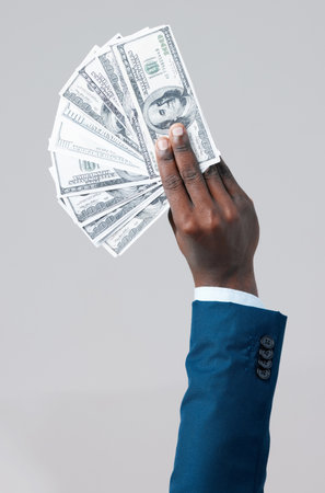 Check out my stash of cash. Studio shot of an unrecognisable businessman showing off US dollars against a grey background.の写真素材