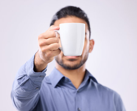 Hand, coffee cup and studio with business man for drink, energy and health to start morning by background. Businessman, young entrepreneur and holding mug for tea, latte or matcha by gray backdropの写真素材