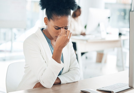 Stress, headache and sad woman on computer with career burnout, anxiety or mental health risk in office. Crying, pain and depression of tired business person with anxiety for mistake, fail or fatigueの写真素材